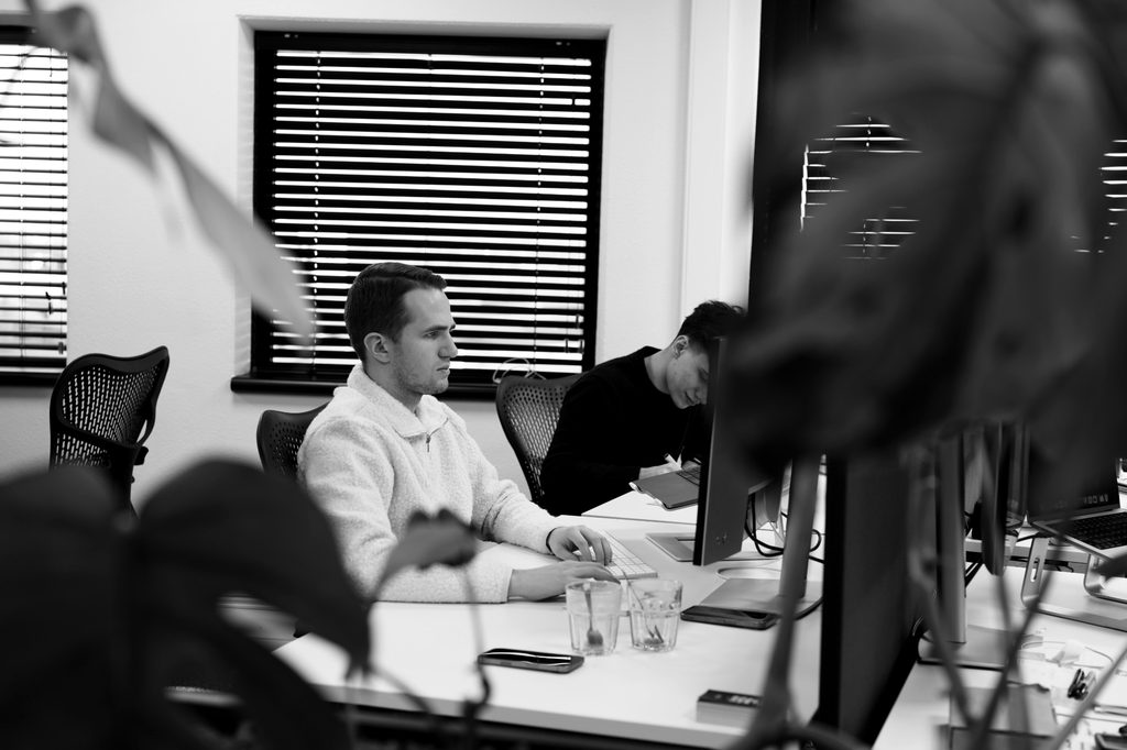 Twee collega's werken geconcentreerd achter hun bureau bij het raam